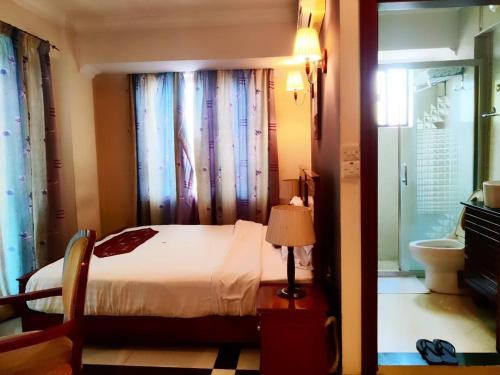 a bedroom with a bed and a window and a lamp at Hotel Nikko Towers in Dar es Salaam