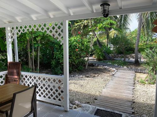 a porch with a wooden walkway and a white pergola at Garance le grand palme in Grand-Bourg