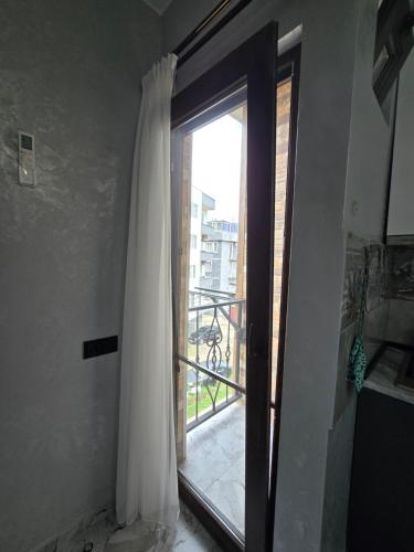 a door with a curtain and a window with a balcony at Batumi Bliss Panoramic Views in Batumi