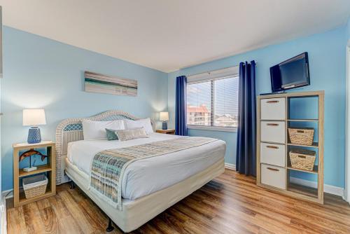 a bedroom with blue walls and a bed with a television at 0601 Seaclusion by Atlantic Towers in Carolina Beach