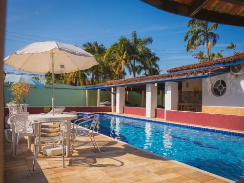a table with an umbrella next to a swimming pool at Villa Di Verona Charm Hotel in Guarujá