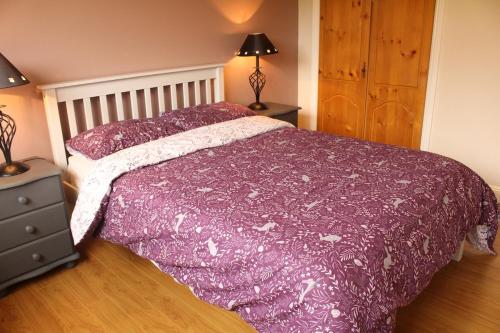 a bedroom with a bed with a purple comforter at Tranquil Carlow Bungalow in Crockaun