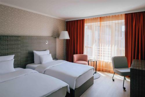 a hotel room with two beds and a window at Pentahotel Leipzig in Leipzig
