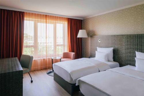 una camera d'albergo con due letti e una finestra di Pentahotel Leipzig a Lipsia