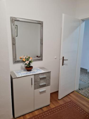 un baño con espejo y un jarrón de flores en un mostrador en Apartmani Cool & Chill, en Gradac