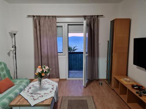 Una sala de estar con un jarrón de flores sobre una mesa. en Apartmani Cool & Chill, en Gradac