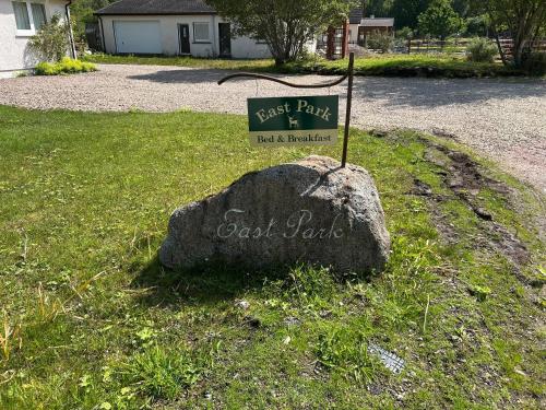 a rock with a sign on top of it at East Park Taigh na nighean in Roybridge