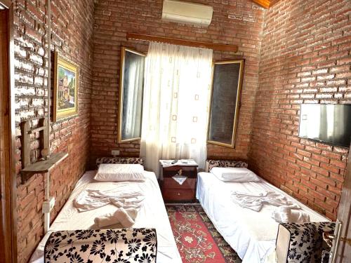 a room with two beds and a brick wall at Golden Campsite Villas in Berat