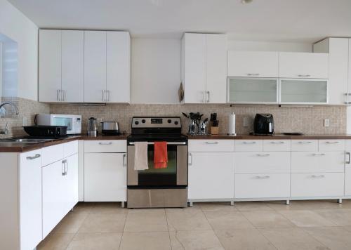 a kitchen with white cabinets and a stove top oven at Whispering Palms Villa in Jolly Harbour in Jolly Harbour