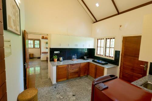 a kitchen with wooden cabinets and a counter top at Nellu - Tranquil Pool Villa & Organic Farmstay near Varkala in Trivandrum