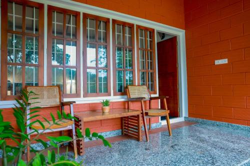 a porch with two chairs and a table and windows at Nellu - Tranquil Pool Villa & Organic Farmstay near Varkala in Trivandrum