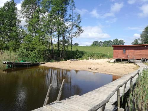 a wooden bridge over a body of water with a building at Pokoje Apartamenty w Dolinie Rospudy in Skazdub Stary