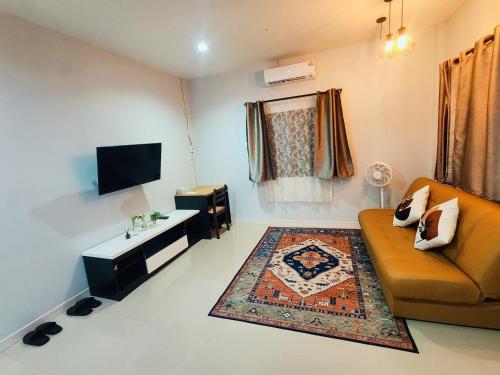 a living room with a couch and a tv at Damiya Peaceful House in Ban Bo Dan