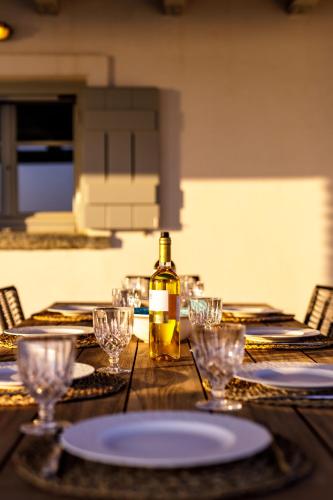 a bottle of wine sitting on a wooden table with glasses at Villa Kouneli - an exceptional holiday in Koundouros