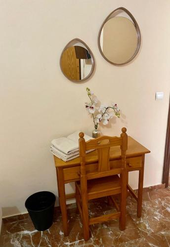 a table with a mirror and a vase with flowers on it at La Vega Rooms in Huelva