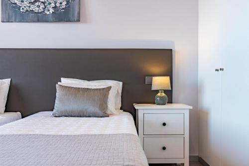 a bedroom with a bed and a night stand with a lamp at Villa Pinheira IV -Heated swimming pool and jacuzzi in Calheta