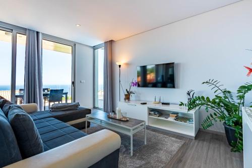 a living room with a blue couch and a table at Villa Pinheira IV -Heated swimming pool and jacuzzi in Calheta