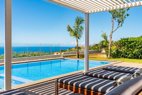a villa with a swimming pool and the ocean at Villa Pinheira IV -Heated swimming pool and jacuzzi in Calheta