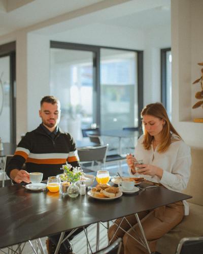 a man and a woman sitting at a table with food at Hotel Capris Capodistria Boutique in Koper