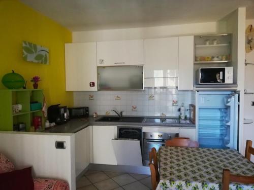 a small kitchen with white cabinets and a table and a tableablish at La Vache Qui Roule -CIR Charvensod 0037 in Aosta