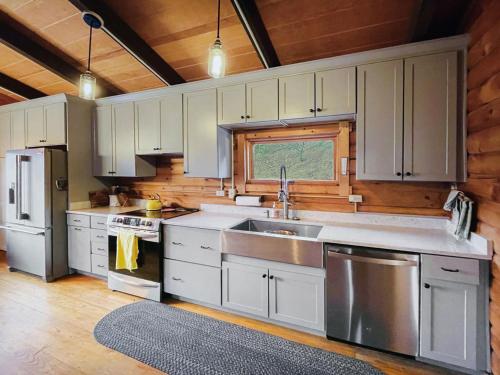 a kitchen with white cabinets and stainless steel appliances at Log Cabin w Fireplace EV Station Solar Powered in Great Cacapon