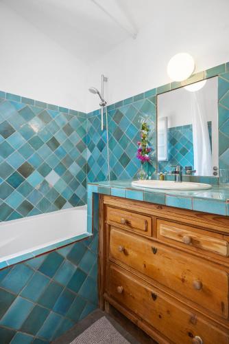 La salle de bains est pourvue de carrelage bleu, d'un lavabo et d'un miroir. dans l'établissement Lilie House, à Bormes-les-Mimosas