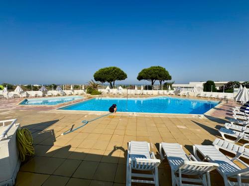 une personne se tient près d'une piscine avec des chaises dans l'établissement Vue panoramique sur le port - Calme & Confort, au Grau-du-Roi