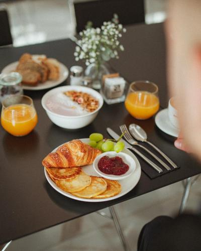 a table topped with plates of breakfast foods and oranges at Hotel Capris Capodistria Boutique in Koper