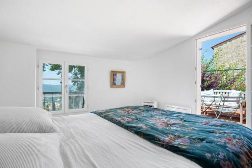 une chambre blanche avec un lit recouvert d'une couverture fleurie dans l'établissement Lilie House, à Bormes-les-Mimosas
