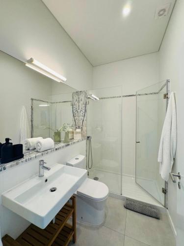 a white bathroom with a sink and a shower at Casa do Meio #5 in São Martinho do Porto
