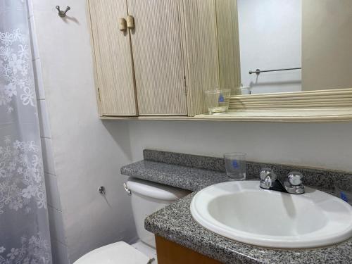 a bathroom with a sink and a toilet and a mirror at Apto para 3 A pasos del Downtown y Playa Veleros in Pampatar