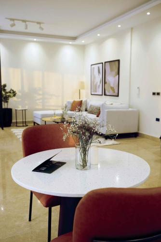 a living room with a table with flowers on it at Homtel Residence AUC South 90s in Cairo