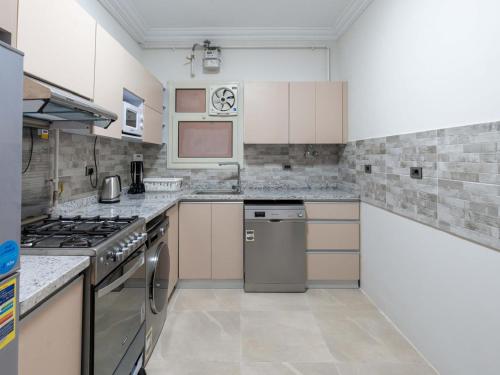a kitchen with white cabinets and a stove top oven at Homtel Residence AUC South 90s in Cairo
