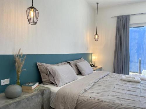 a bedroom with a large bed and two pendant lights at La Ventana Hostel in La Ventana