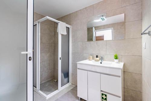 ein Badezimmer mit einem weißen Waschbecken und einer Dusche in der Unterkunft Casa do Manuel Maria in Estreito da Calheta