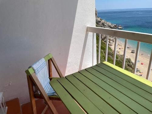 a chair sitting on a balcony with a view of the beach at O som das ondas - vista soberba de mar in Sesimbra