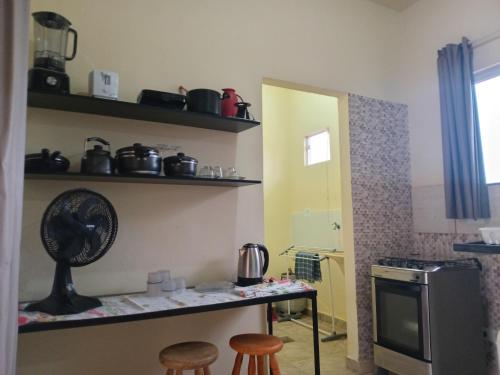 una cucina con bancone, 2 sgabelli e ventilatore di Kitnet Marília a Marília