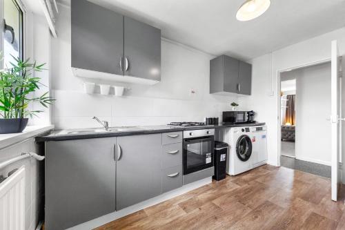 a kitchen with gray cabinets and a washer and dryer at South Stays in London