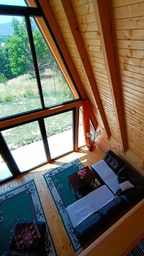 an attic room with a couch in front of a window at ZenFrame Cabin in Tarčin