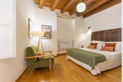 a bedroom with a bed and a green chair at Martini Castello Boutique Apartments - Historic Center & Lift in Cagliari