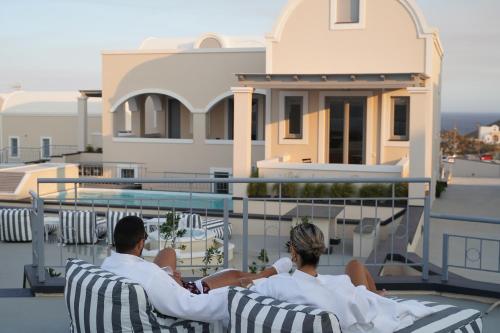 three people sitting in chairs on the balcony of a house at The Noverian Bios Caldera Sunset Suites in Akrotiri