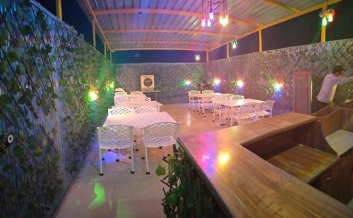 a dining room with white tables and chairs and lights at Modest Rooms By Libra in Khizrābād
