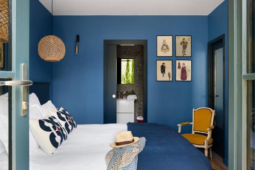 ein blaues Schlafzimmer mit einem Bett und einem Stuhl in der Unterkunft La Maison du Traict Chambres d'hôtes in Le Croisic
