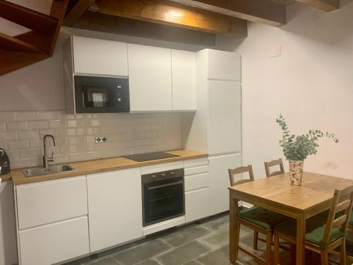 a kitchen with white cabinets and a wooden table at La Caseta del Pont in Camprodon