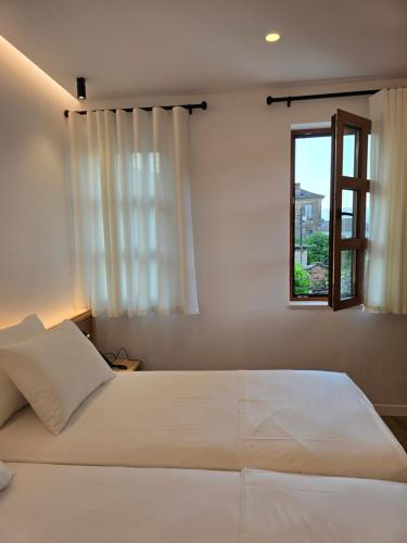 a bedroom with a large white bed with a window at Palorto Inn in Gjirokastër