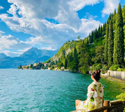 a woman sitting on a fence overlooking a lake at Le Palm House has two bedrooms with the breathtaking view over lake Como in Perledo