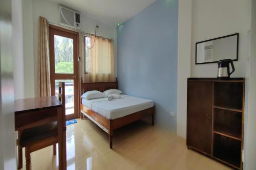 a bedroom with a bed and a desk and a window at Kamalay Pension House in Nagpoyopoyo Island