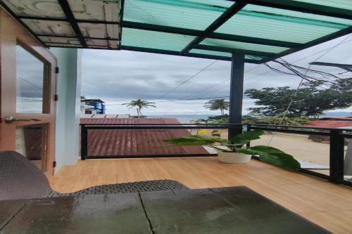 a room with a balcony with a view of the ocean at Kamalay Pension House in Nagpoyopoyo Island
