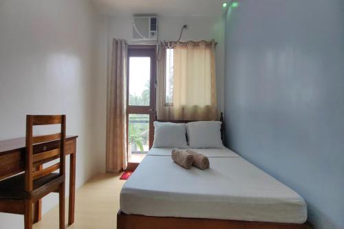 a bedroom with a bed and a desk and a window at Kamalay Pension House in Nagpoyopoyo Island