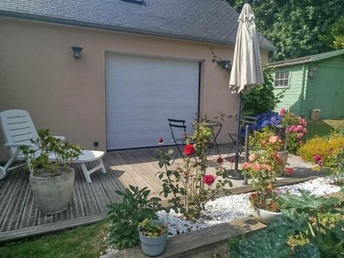 un patio avec un parasol et quelques fleurs et plantes dans l'établissement Les hortensias, à Lannion